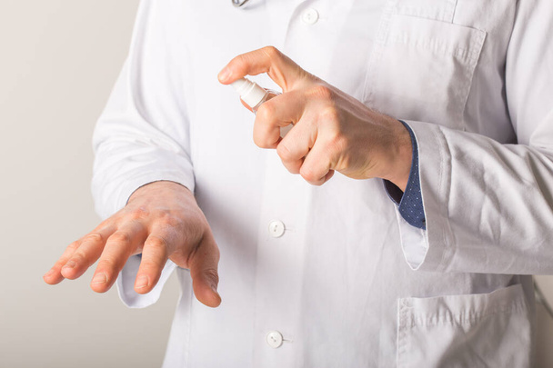 Doktor elleri, beyaz bir arka planda Alkol dezenfektanı ile yıkama elini kullanıyor. 2020 Corona virüs krizinde kendilerini virüs enfeksiyonundan koruyorlar. - Fotoğraf, Görsel