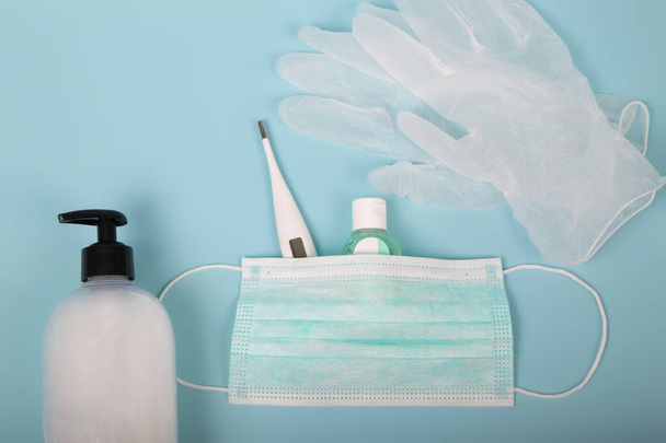 Very important personal hygiene and protection products for treatment. Surgical mask, thermometer, disinfectant gel, latex gloves and liquid hand soap on a blue background. Coronavirus or covid-19 concept. - Photo, Image
