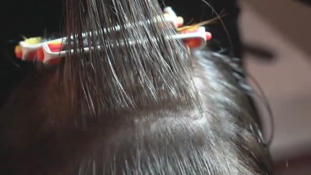 Curl hair on the curl. The hairdresser makes a hairstyle for a child by combing and twisting hair into a curl in a beauty salon. - Footage, Video