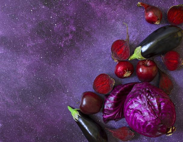 Frutas y verduras púrpuras sobre un fondo púrpura. Col, manzanas, cebollas moradas, remolachas, berenjenas. Hortalizas y frutas frescas de granja en la misma gama de colores.  - Foto, imagen