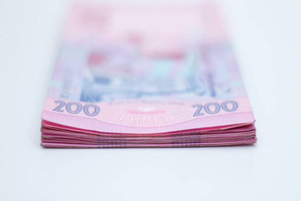 Spousta nových bankovek v nominálních hodnotách 200 ukrajinských hřiven izolovaných na bílém pozadí se stínem. Evropská směna peněz. Ukrajinská měna. Selektivní zaměření - Fotografie, Obrázek