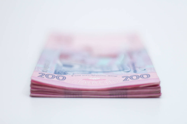 A lot of new banknotes in denominations of 200 Ukrainian hryvnias isolated on a white background with shadow. European money exchange. Ukraine currency. Selective focus - Foto, immagini