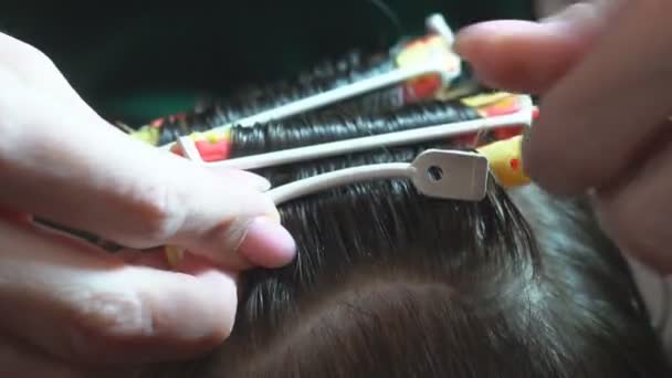 Bouclez les cheveux sur la boucle. Le coiffeur fait une coiffure pour un enfant en peignant et en tordant les cheveux en une boucle dans un salon de beauté
. - Séquence, vidéo