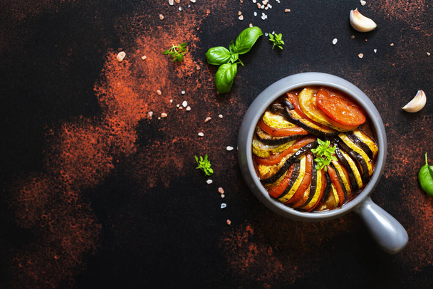 焼きたての夏野菜のラタトゥイユ伝統的なフランス料理は、ベーキングトレイで提供しています。ベジタリアンやダイエットフード。フランス料理/料理。暗い素朴な背景、トップビュー、コピースペース - 写真・画像