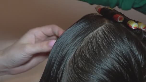 Cabello rizado en el rizo. El peluquero hace un peinado para un niño peinando y retorciendo el cabello en un rizo en un salón de belleza
. - Metraje, vídeo
