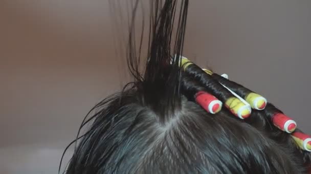 Lockenhaar auf der Locke. Der Friseur frisiert ein Kind, indem er die Haare in einem Schönheitssalon zu Locken kämmt und verdreht. - Filmmaterial, Video