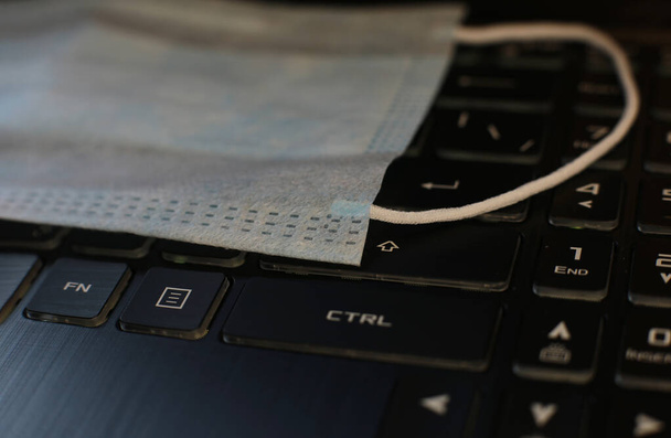 макро фото медицинская маска против вируса лежит на клавиатуре, карантин удаленной работы
 - Фото, изображение