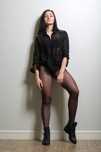 Fashionable young beautiful woman in black nylon tights, stylish leather boots and black blouse - Foto, Bild