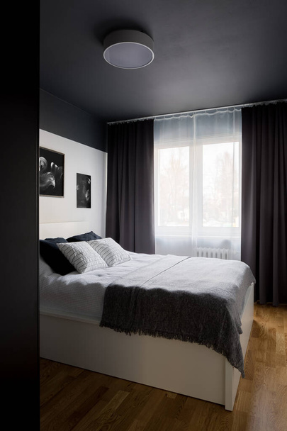 Designed bedroom with stylish black ceiling and white double bed - Foto, Bild