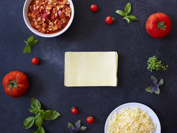 Ingredients for cooking lasagna. Recipe for homemade Italian lasagna with tomato sauce and meat. Tomatoes, basil, meat sauce, mozzarella cheese, lasagna noodles. Italian food. Top view. Copy space - Photo, Image