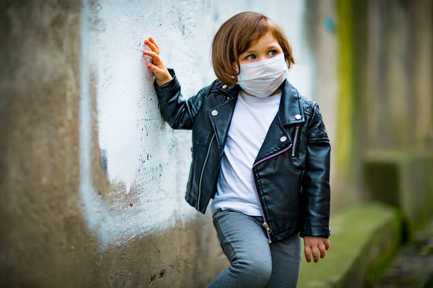 little girl on a walk in a medical mask - 写真・画像