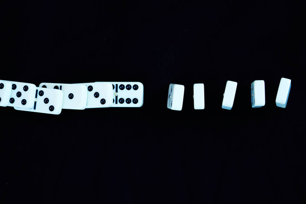 White domino falling in straight line from left to right with a break. Concept for coronavirus covid-19, with social distancing the spread stops - Photo, Image