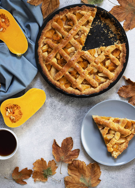 Thanksgiving homemade pumpkin pie. Sliced Pumpkin Pie. Cup of tea, autumn leaves, pumpkin. Light gray background, top view, copy space - Photo, Image