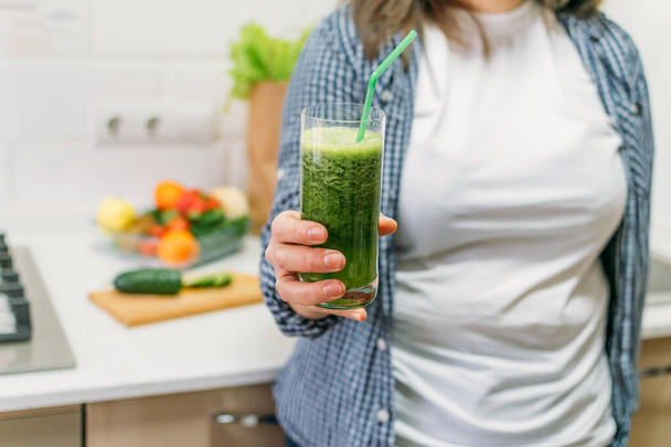Green Smoothies for Weight Loss. Plus size woman holding in hand glass with slimming Green Smoothie, juice. - Foto, afbeelding