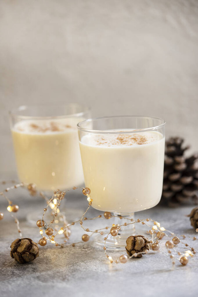 Eggnog παραδοσιακό σπιτικό Χριστουγεννιάτικο και Πρωτοχρονιάτικο ποτό με κανέλα και μοσχοκάρυδο. Χειμερινές διακοπές. Φωτεινό φόντο. Επιλεκτική εστίαση - Φωτογραφία, εικόνα