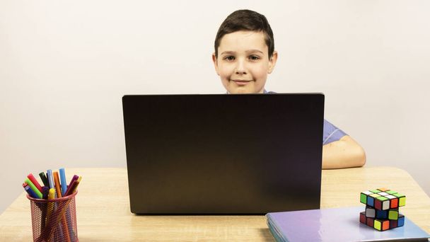 young guy looking at the camera. schoolboy boy sitting at a computer. Online classes. Home education. Quarantine. Copyspace - Photo, image