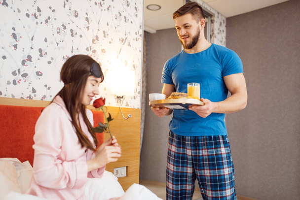 Romantic love couple, breakfast in bed at home, good morning. Harmonious relationship in young family. Man and woman resting together in their house, carefree weekend - Φωτογραφία, εικόνα