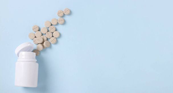 Homeopathische hoest pillen mucaltin in een pot op een blauwe achtergrond, Kopieer ruimte, Uitzicht van boven - Foto, afbeelding