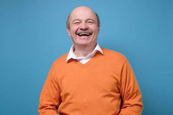 Smějící se pozitivní španělsky starší pohledný muž s dobrou náladou pocit pozitivní. Studio záběr na modré zdi. - Fotografie, Obrázek