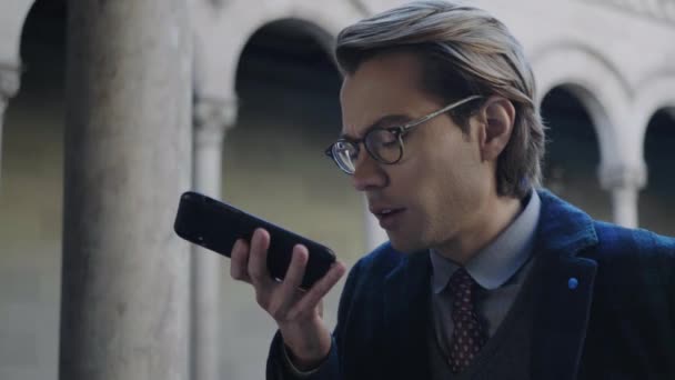 Diák hangüzenet rögzítése mobilon. Mobiltelefont használó férfi a szabadban - Felvétel, videó