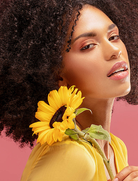 Beautiful afro woman posing with yellow sunflower on pink pastel studio background. Concept of women's and mother's day. Spring, summer feelings. Girl power. - Foto, Bild