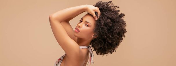 Beauty portrait of beautiful emotional african american girl with curly hair on beige studio background. - Foto, Imagen