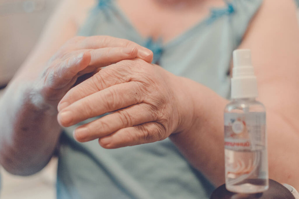 Prevention of Coronavirus Disease COVID-19. Old woman use an alcohol-based hand sanitizer with 60 alcohol, hands close up. How to Prepare for the Coronavirus. - Photo, Image