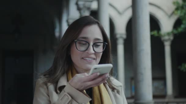 Student nimmt Sprachnachricht auf Smartphone auf. Lady geht in College-Flur - Filmmaterial, Video