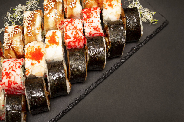 Grande conjunto de sushi com rolos de asori em um quadro negro de ardósia. Há espaço de cópia para menus ou entradas
. - Foto, Imagem
