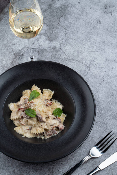 Vertical photo of farfalle with beef and sun-dried tomatoes on grey stone table with copy space - Foto, imagen