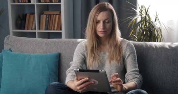 Attractive lady using tablet while relaxing on couch - Footage, Video