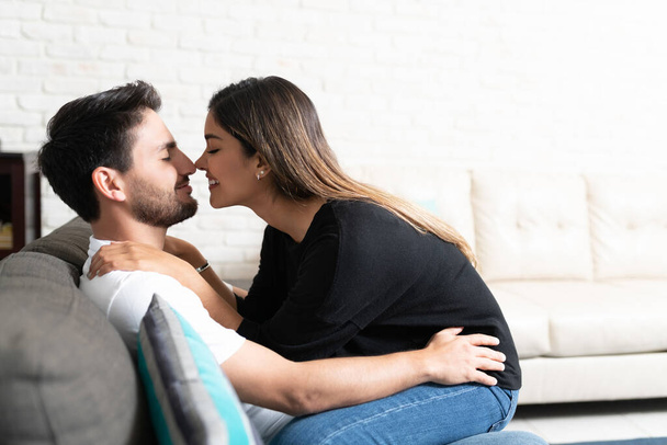 Hymyilevä romanttinen latina tyttöystävä istuu sylissä poikaystävä kotona
 - Valokuva, kuva