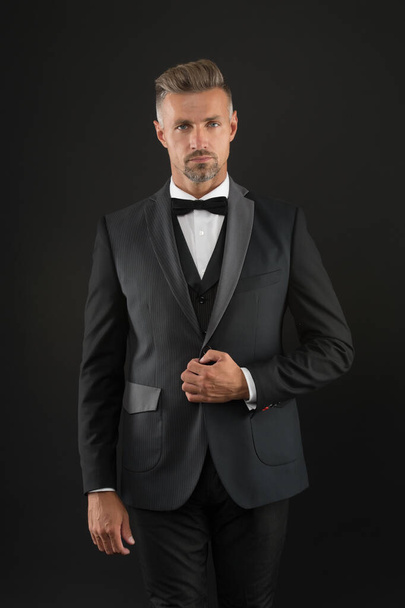 Appreciate classics. Bearded man with formal look. Hipster black background. Brutal man in tuxedo suit. Classic can make man look smarter. Black tie. Fashion shop. Buy clothes. Menswear concept - 写真・画像