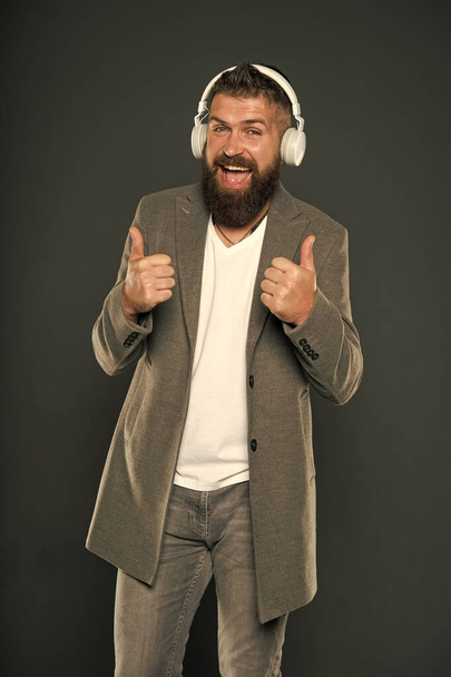 Give thumbs ups to technology. Happy hipster wear wireless headphones. Bearded man enjoy listening to music. Stereo sound technology. New technology. Technology for business and fun - Фото, зображення