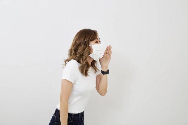Junge Asiatin mit Gesichtsmaske isoliert auf hellgrauem Hintergrund. Grippeepidemie, Stauballergie, Virenschutz. Luftverschmutzungskonzept für Städte - Foto, Bild