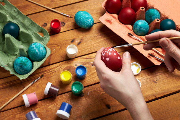 Painting eggs. Woman's hands paint eggs for Easter day. Preparing for Easter. - Zdjęcie, obraz