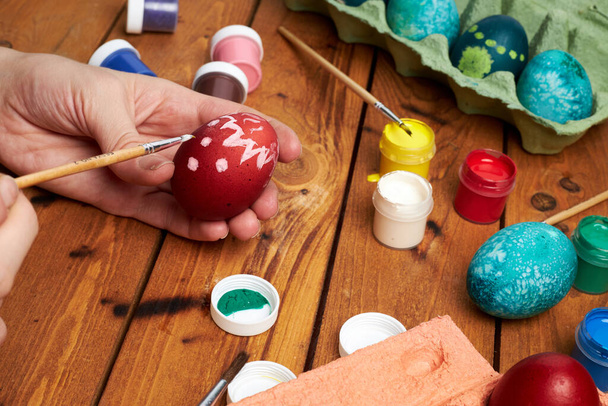 Happy Easter! Woman's hands paint eggs for Easter day. Preparing for Easter. - Фото, изображение