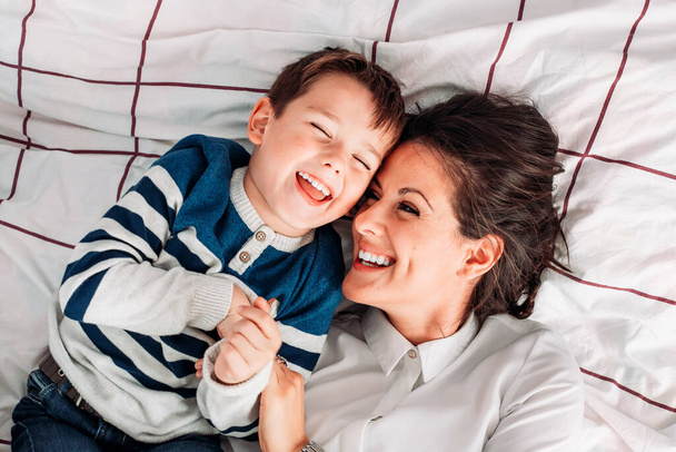Mom having great time with her son in bed. Parent kid relationship. Mothers day - 写真・画像