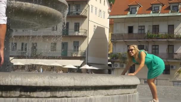SLOW MOTION: Woman splashes water at her boyfriend during a trip in Ljubljana. - Footage, Video
