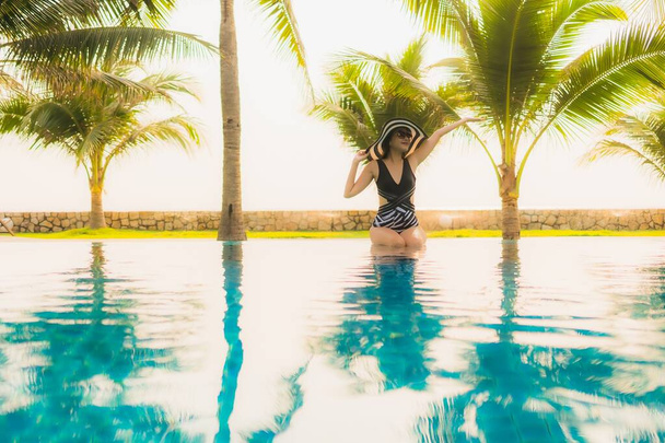 Portrét krásná mladá asijská žena relaxovat kolem venkovního bazénu v hotelovém resortu s palmou při západu slunce nebo východu slunce pro volný čas dovolenou - Fotografie, Obrázek