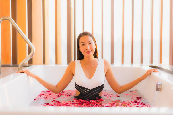 Portret piękna młoda azjatycka kobieta szczęśliwy uśmiech uwolnienie w wannie z różanym kwiatem do koncepcji spa - Zdjęcie, obraz