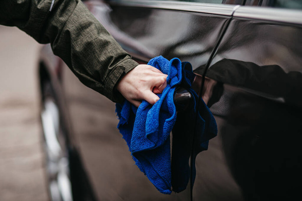 Man's hand disinfecting door handle of brown car by blue disinfectant wipe. Prevent the virus and bacterias, Prevent covid19, corona virus, Alcohol Sanitizer. Hygiene concept at home. - 写真・画像