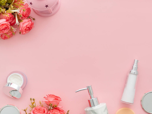 Beauty background with body cosmetics products, roses flowers on pastel light pink desktop background with copy space. Modern spring skin care layout, top view, flat lay.  - 写真・画像