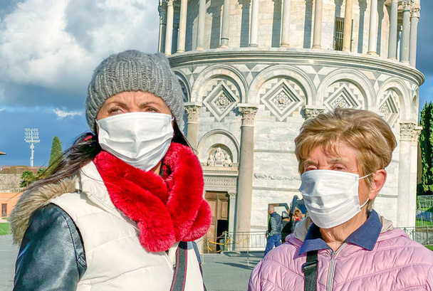 Emergencia por brote de coronavirus. Mujer con su madre visitando lugares emblemáticos con máscaras protectoras. - Foto, Imagen