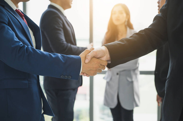 アジアのビジネスマンチームは成功を扱うために握手をする。握手を交わし事務所での会議を終えたビジネスマンのチーム. - 写真・画像