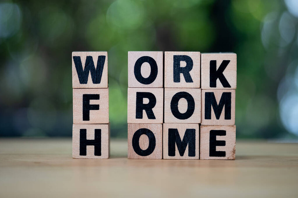 Wooden blocks with the word work from home on wood table with nature blur background - Fotó, kép