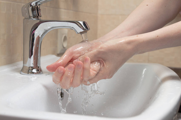 Higiena. Czyszczenie rąk. Mycie rąk czystą wodą. Kobieca ręka. Chroń się przed pandemią COVID-19. Zdjęcie z bliska. - Zdjęcie, obraz