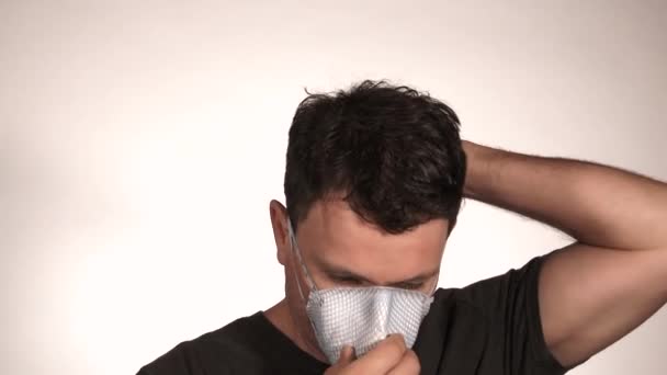 Person zieht zum Schutz eine N95-Atemschutzmaske an und zieht sie dann aus, im Studio isoliert auf weiß mit Modellfreigabe. - Filmmaterial, Video