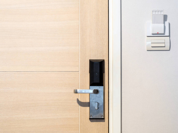 Modern wooden door with handle equipment and key card socket at the wall of the hotel room - Photo, Image