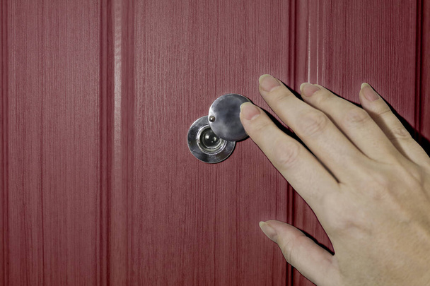 Een vrouwelijke hand opent de luiken van het kijkgaatje in de voordeur. Het begrip veiligheid en voorzichtigheid. - Foto, afbeelding